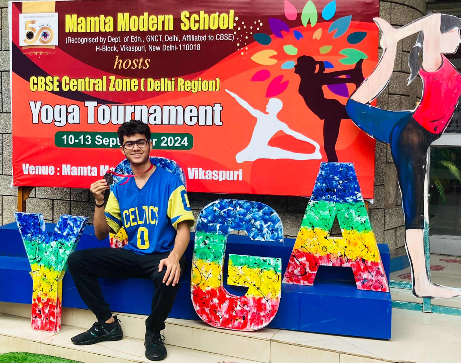 A young representative of the school displaying his award for participationg in yoga competition.